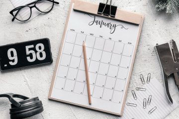 clipboard with calendar placed on desk amidst stationery